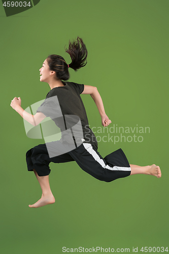 Image of Freedom in moving. Pretty young woman jumping against green background