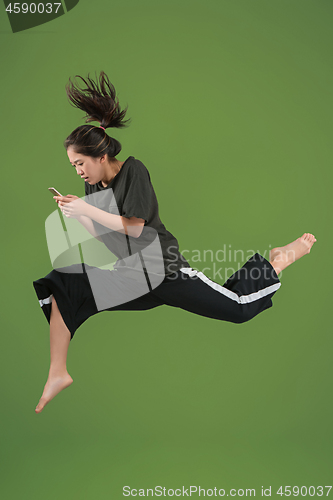 Image of Freedom in moving. Pretty young woman jumping against green background