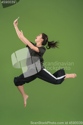 Image of Freedom in moving. Pretty young woman jumping against green background