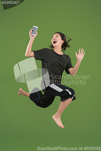 Image of Freedom in moving. Pretty young woman jumping against green background