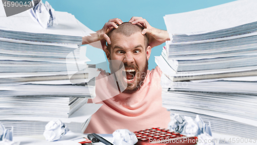 Image of Frustrated overwhelmed executive working in the office and overloaded with paperwork