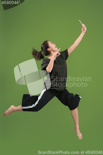 Image of Freedom in moving. Pretty young woman jumping against green background