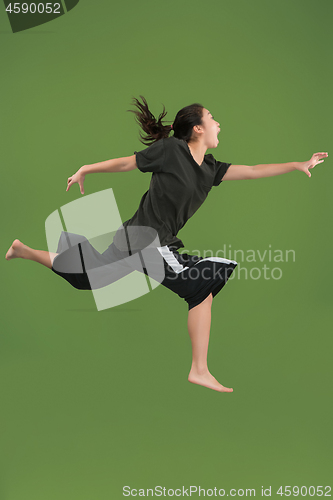 Image of Freedom in moving. Pretty young woman jumping against green background