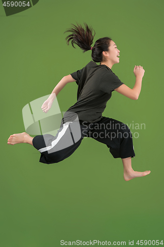 Image of Freedom in moving. Pretty young woman jumping against green background