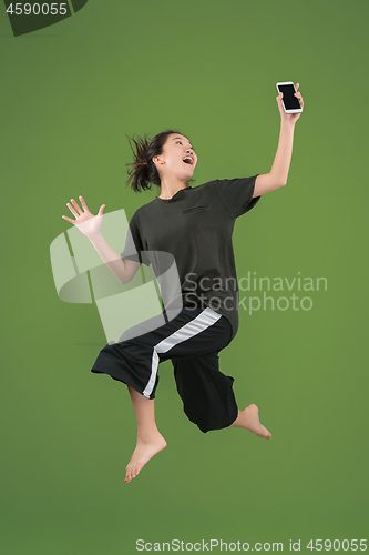 Image of Freedom in moving. Pretty young woman jumping against green background