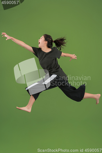 Image of Freedom in moving. Pretty young woman jumping against green background