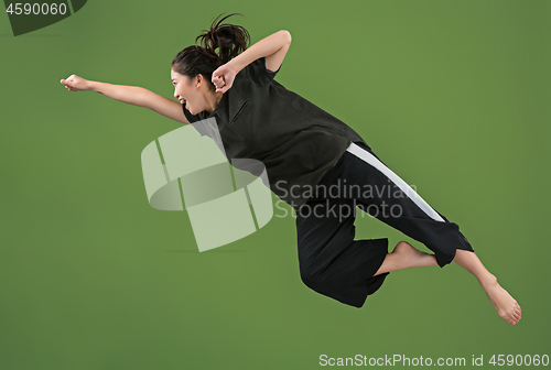 Image of Freedom in moving. Pretty young woman jumping against green background