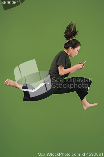 Image of Freedom in moving. Pretty young woman jumping against green background