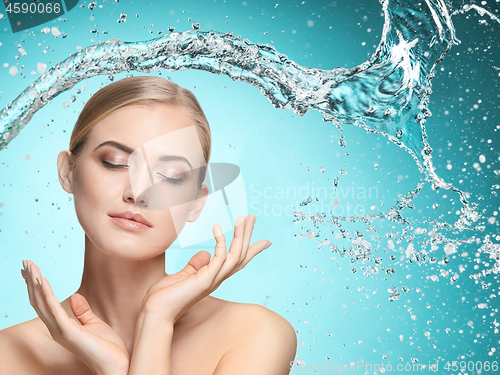 Image of Beautiful female model with splashes of water in her hands.
