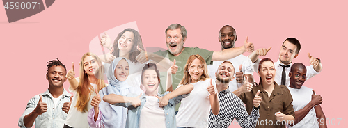 Image of The happy business women and men standing and smiling against pink background.