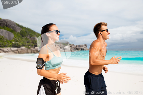 Image of couple with phones and arm bands running on beach