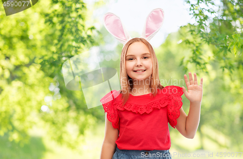 Image of happy girl wearing easter bunny ears waving hand