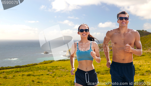 Image of couple in sports clothes running along on beach