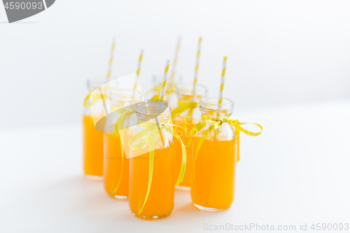 Image of orange juice in glass bottles with paper straws