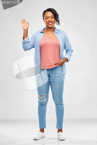 Image of happy african american woman waving hand