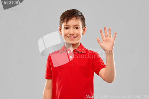 Image of portrait of smiling boy in red t-shirt waving hand