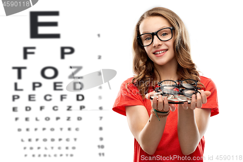 Image of teenage girl holding glasses over eye test chart