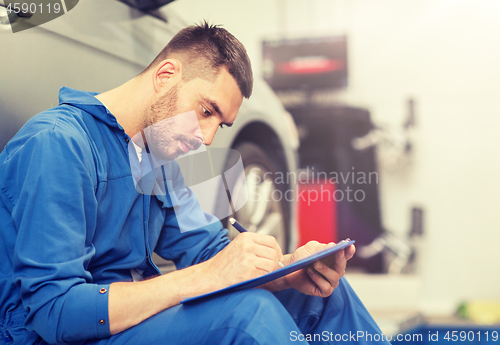 Image of auto mechanic man with clipboard at car workshop