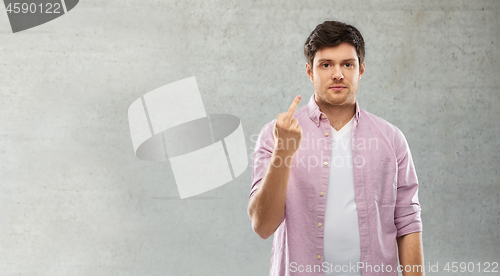 Image of man showing middle finger over grey concrete wall