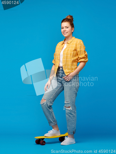 Image of red haired teenage girl with short skateboard