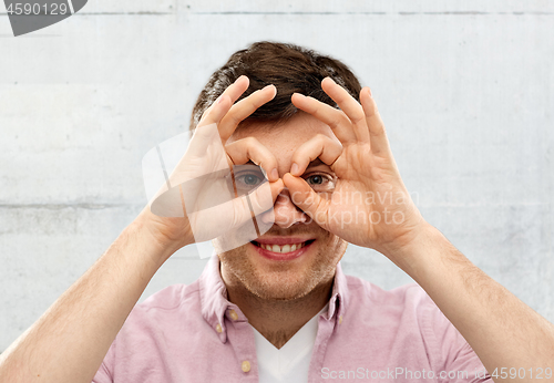 Image of young man looking through finger glasses