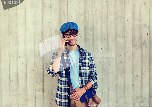 Image of man with bag calling on smartphone at street wall