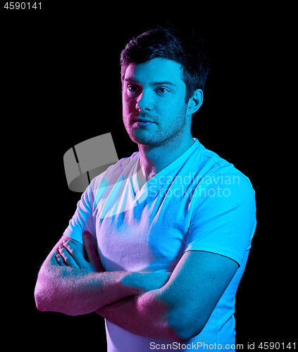 Image of man with crossed arms over neon lights in darkness