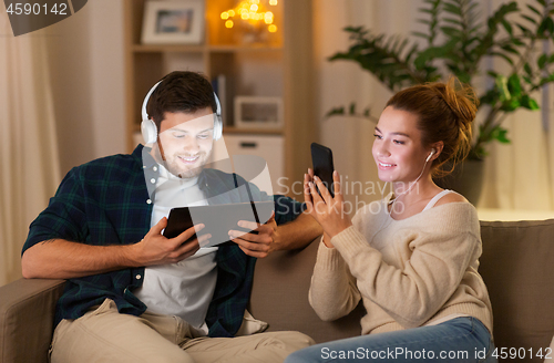 Image of couple with gadgets listening to music at home