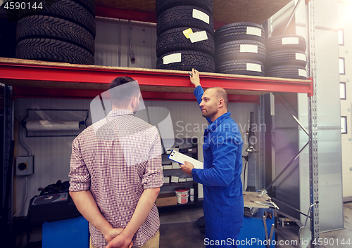 Image of auto mechanic and man with tires at car shop