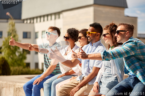 Image of friends in sunglasses showing thumbs up in city