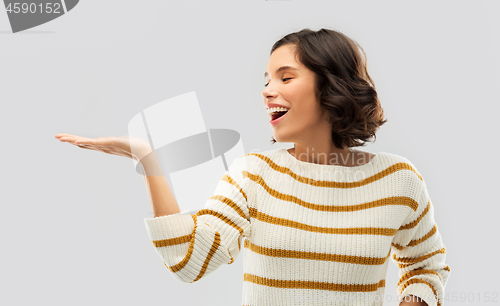 Image of smiling young woman holding empty palm