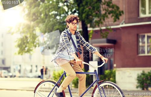 Image of young hipster man with bag riding fixed gear bike