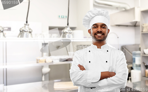 Image of happy indian chef in toque at restaurant kitchen