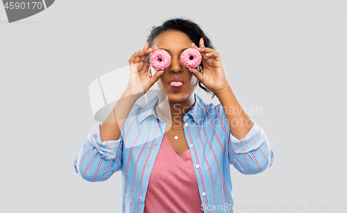 Image of happy african american woman with eyes of donuts