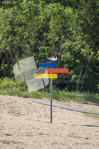 Image of Colorful wooden signpost of directions on a sand beach.