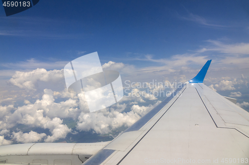 Image of Wing of the plane on blue sky cloudy background.