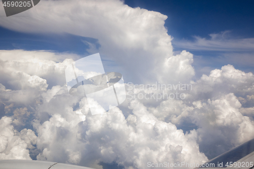 Image of View from plane porthole to the cloudy blue sky.