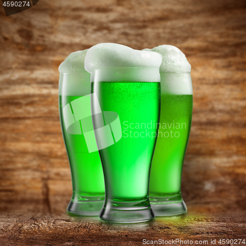 Image of Alcoholic green beer in the glasses on a blurred wooden.