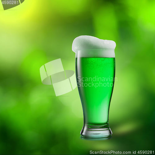 Image of Glass of green beer on a blurred natural background.