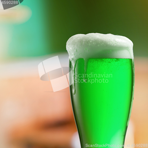 Image of Glass of light green beer with thick foam.
