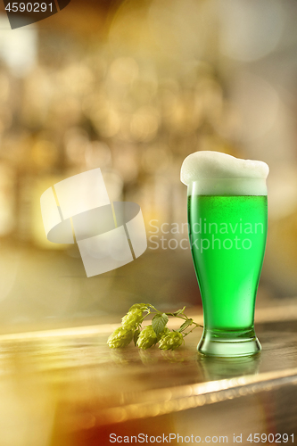 Image of Glass of fresh green beer on a table in a bar.