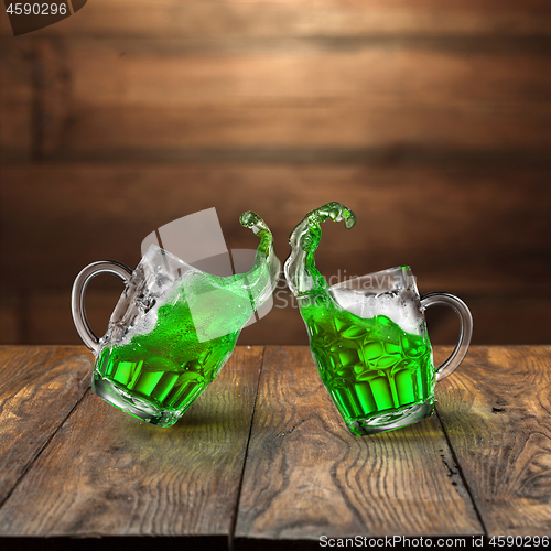 Image of Fresh green beer splashes from two flying beer mugs.