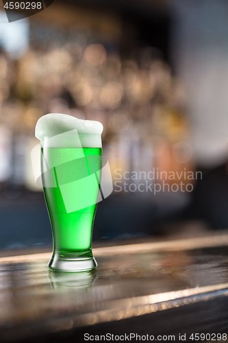 Image of Glass of light green beer on a background of pub.