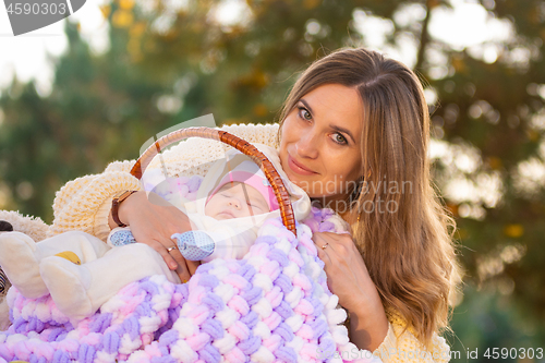 Image of Mom hugs baby sleeping in basket