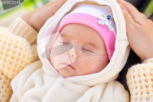 Image of Portrait of a two-month-old baby sleeping on mom\'s feet in a park