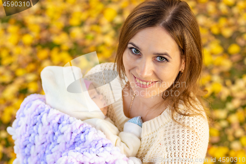Image of Mom with a smile walks in the park with the baby and looked into the frame