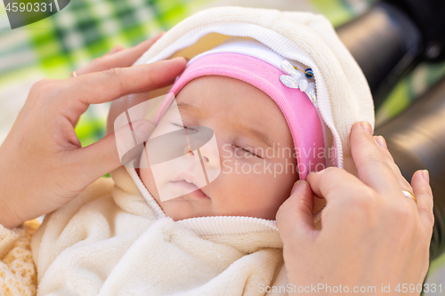 Image of Mom fixes the cap of a two-month-old baby