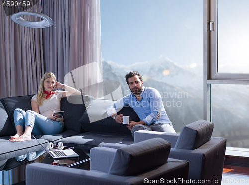 Image of couple relaxing at  home with tablet computers