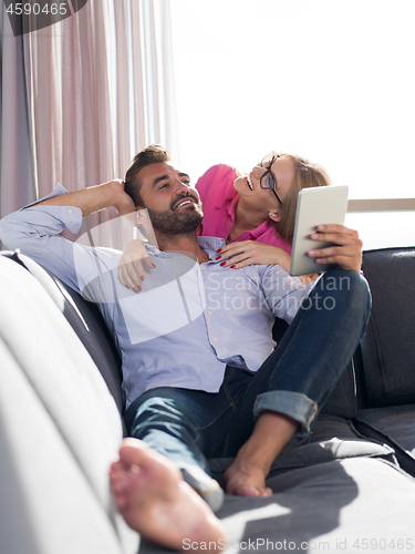 Image of couple relaxing at  home with tablet computers