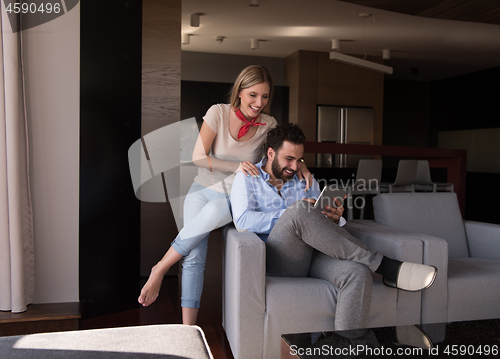 Image of couple relaxing at  home with tablet computers